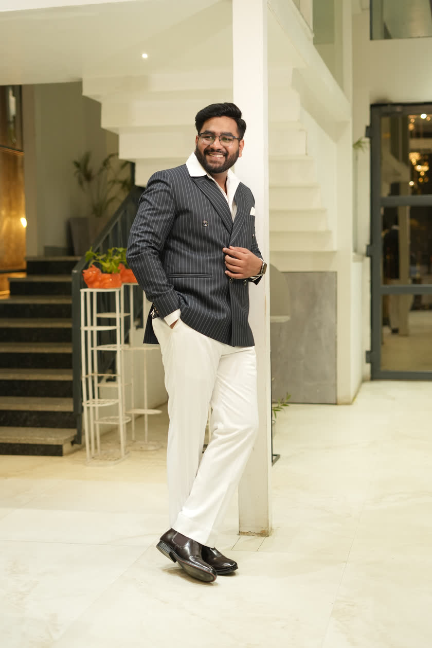 Harsh Agarwal standing in a pinstripe double-breasted suit, smiling